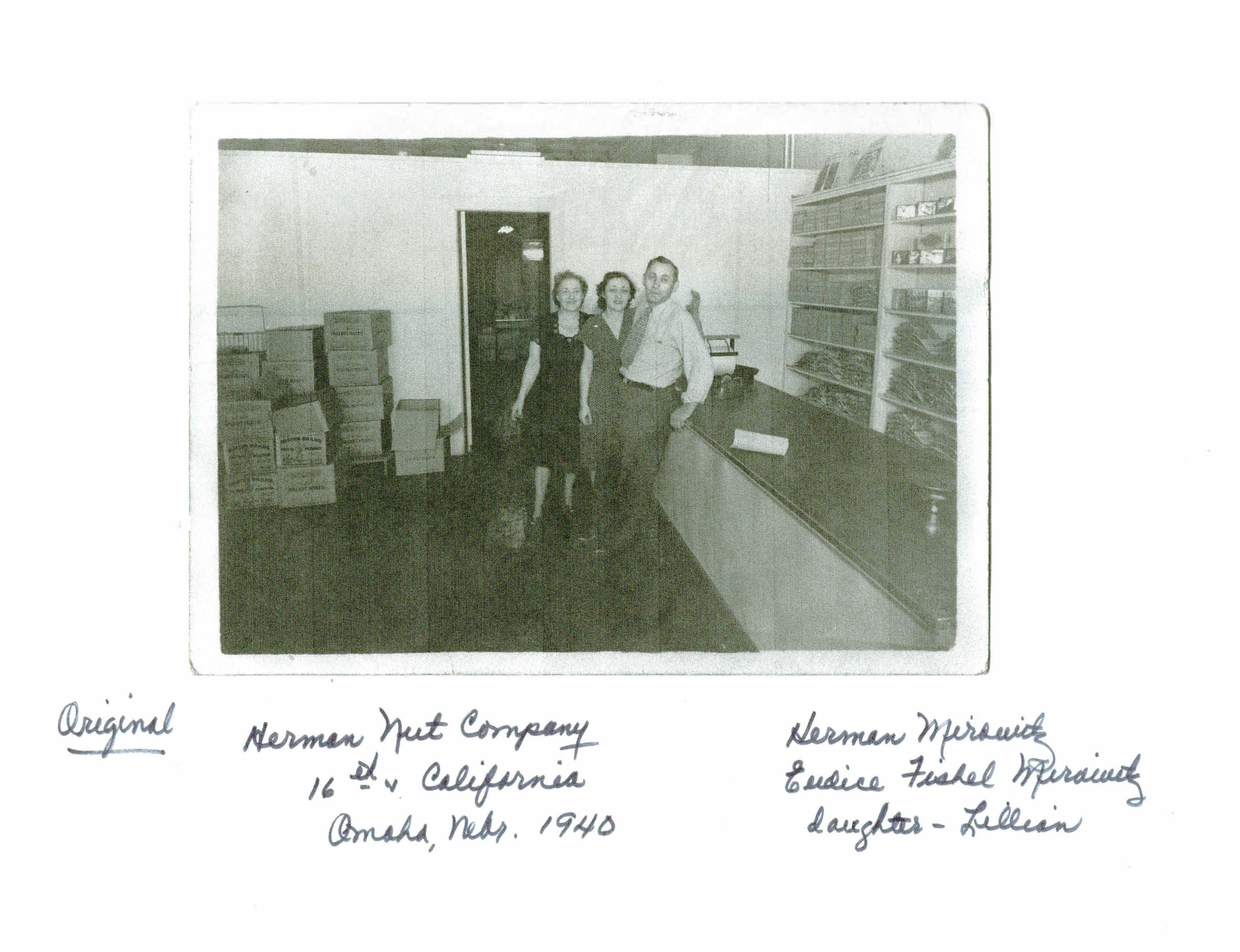 Vintage black and white photo of three people in a store with shelves and boxes.