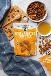 Honey roasted chipotle peanuts packaging with peanuts and honey on a table