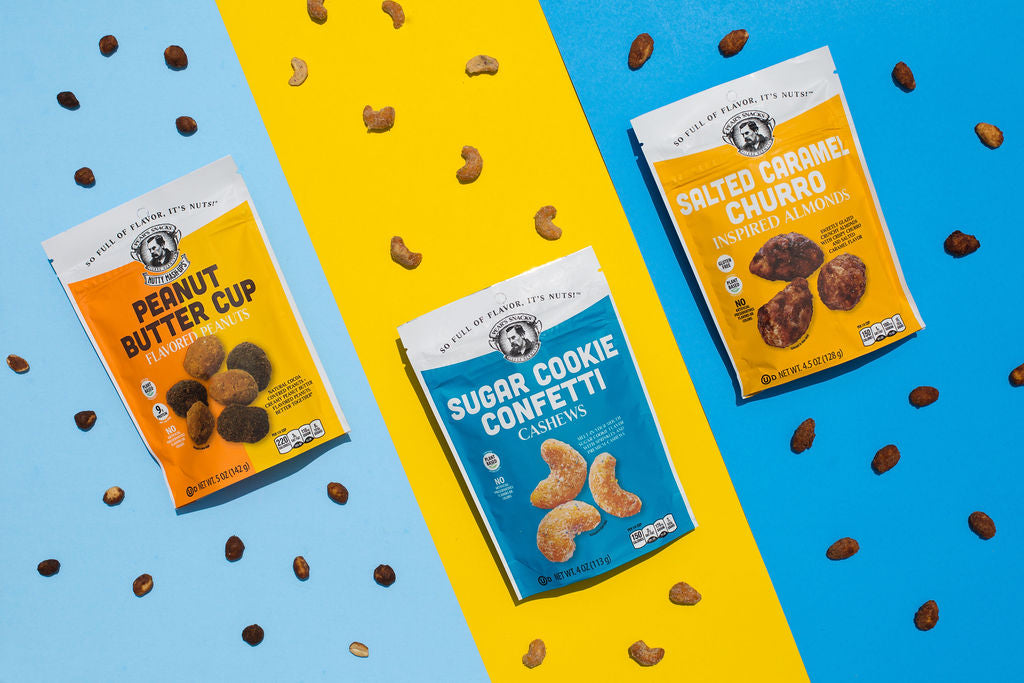 Three packages of different flavored cookies on a blue and yellow background with scattered nuts.