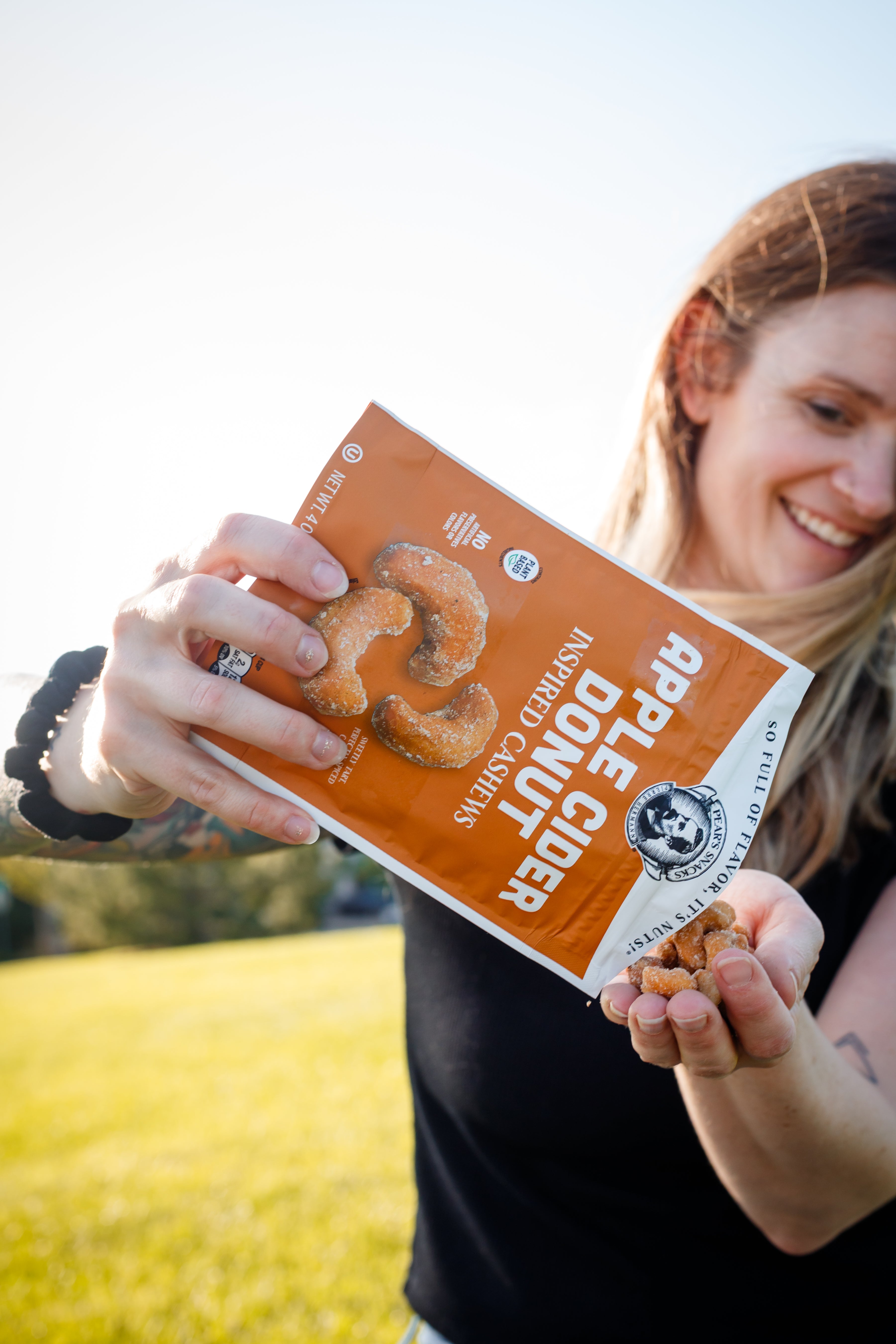 Person holding a bag of Apple Cider Donuts Cashews with a scenic background